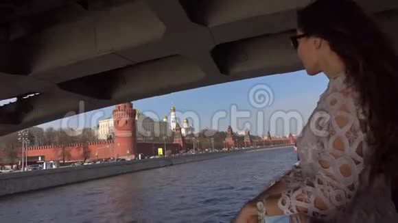 站在船甲板上经过莫斯科克里姆林宫的年轻女子视频的预览图