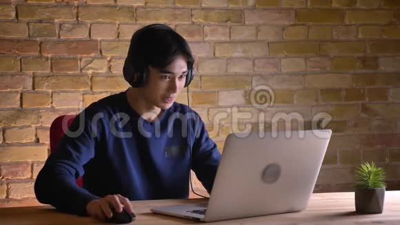 戴着耳机笔记本电脑和视频通话的年轻韩国男学生的特写照片视频的预览图