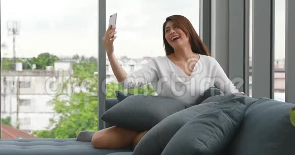 亚洲女人坐在沙发上戴上耳机视频的预览图