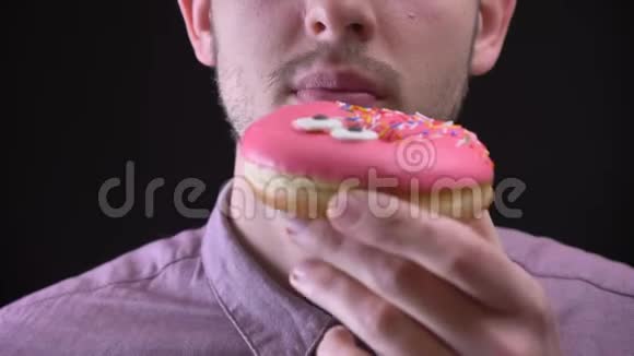 特写人物肖像咬和咀嚼美味的釉粉色甜甜圈与五彩薯片和眼睛黑色视频的预览图