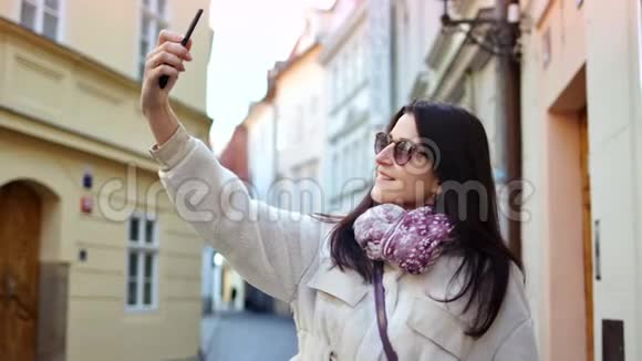 微笑女游客自拍使用智能手机摆姿势环绕历史建筑视频的预览图