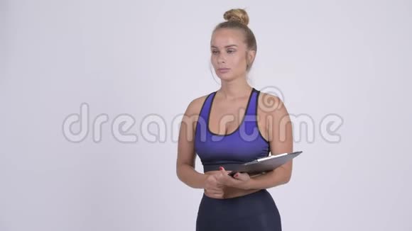 年轻的金发女子作为健身教练说话和拿着剪贴板视频的预览图