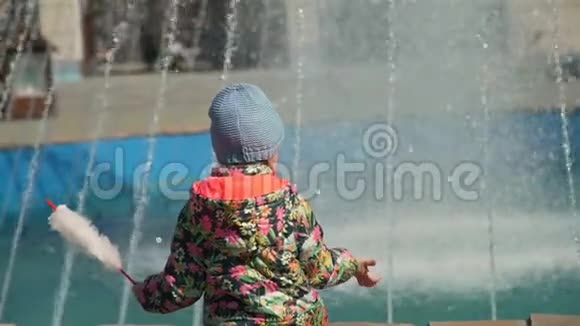 小女孩在喷泉附近吃棉花糖视频的预览图