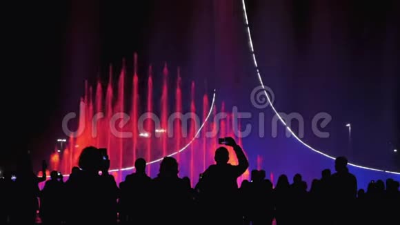 在光节期间五颜六色的喷泉欣赏城市夜景灯光和音乐的人群视频的预览图