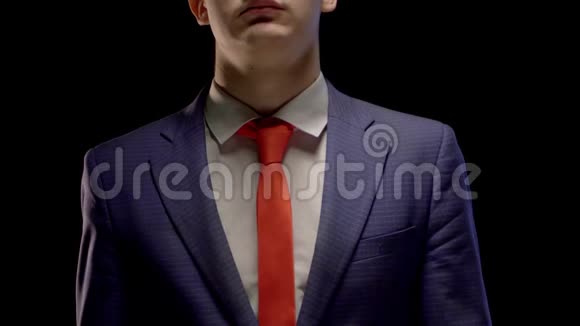 一个穿着简单的蓝色西装和白色衬衫的年轻人整齐地伸直了红领带的手视频的预览图