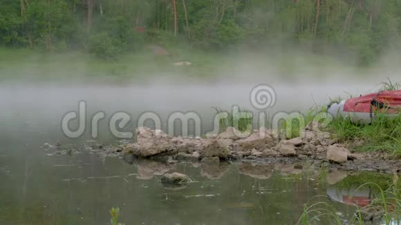 平静的湖边有褐色的石头和红色的小船视频的预览图