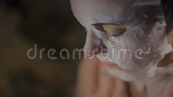 一个戴着恢复活力面具的女人的特写脸看着智能手机屏幕视频的预览图