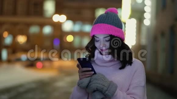 年轻的美女晚上在城里用手机视频的预览图