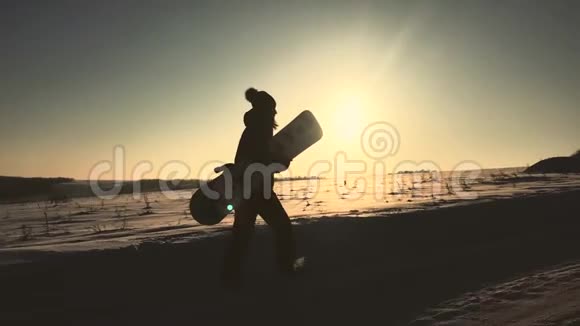 剪影女孩滑雪板行走与滑雪板在山顶在日落视频的预览图