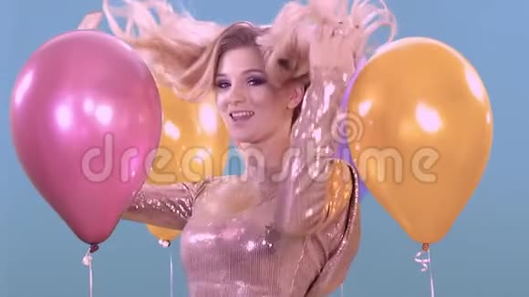 一个年轻的金发女孩在生日时穿着一件漂亮闪亮的裙子在气球之间跳舞视频的预览图