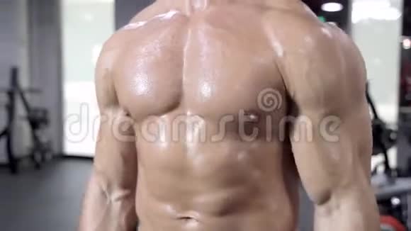 一个肌肉发达的男人赤裸的躯干在健身房锻炼视频的预览图