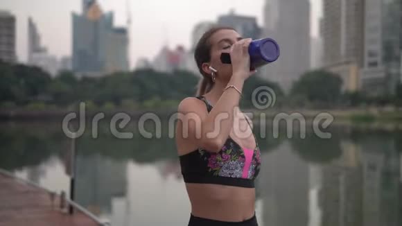 一位女士在美加波利斯市公园晚上运动后喝着蓝色健身杯视频的预览图