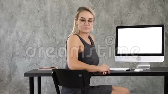 傲慢的自由职业女性在办公室摆姿势看着你查看到计算机屏幕白色显示器视频的预览图