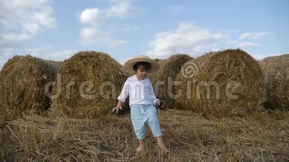 穿着白衬衫戴草帽的男孩光着脚在斜坡上视频的预览图