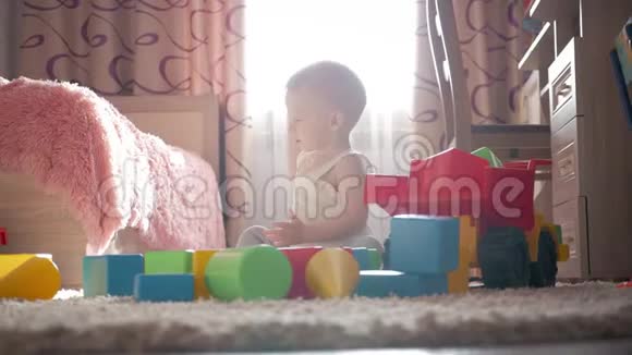 可爱的小男孩戴着帽子玩具躺在家里的地板上视频的预览图