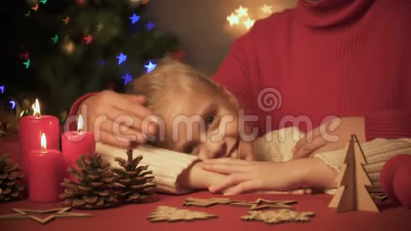 妈妈拥抱和抚摸小可爱的女孩桌子上有圣诞装饰树闪闪发光视频的预览图