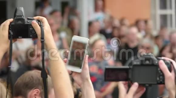 一群人手持智能手机和数码单反相机拍摄视频视频的预览图