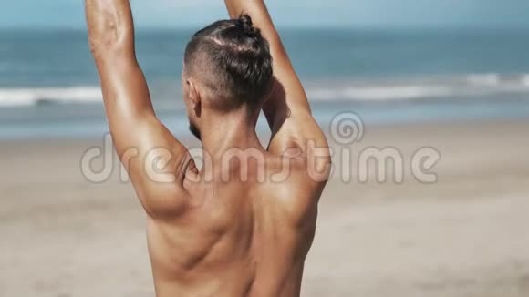 背面观看男子与运动身体做瑜伽运动与海洋背景关闭视频的预览图