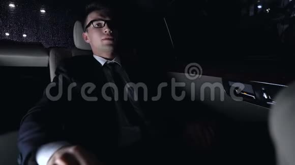 工作过度的商人摘下眼镜坐在汽车疲劳的后座上视频的预览图