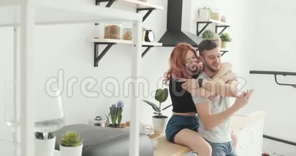 快乐的一对夫妻在家厨房用智能手机上网玩得开心视频的预览图