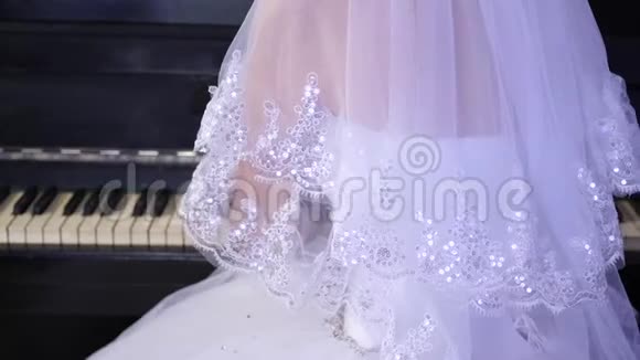 穿着白色球裙的女孩弹钢琴新娘在钢琴上演奏一首音乐音乐生意视频的预览图
