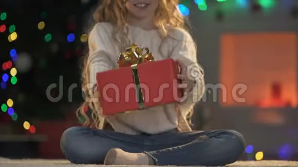 小女孩拿着圣诞礼物对着镜头节日装饰闪闪发光视频的预览图