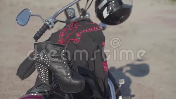 带高跟鞋和黑色和红色连衣裙的加钉鞋躺在摩托车特写上戴着头盔的摩托车视频的预览图