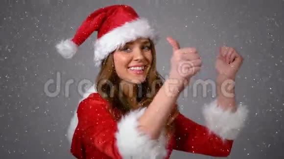一个穿着桑塔服的快乐女孩被大雪覆盖竖起大拇指视频的预览图