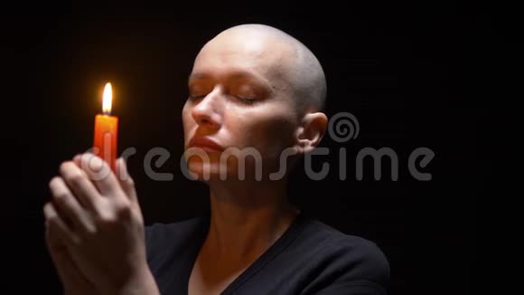 一个在黑色背景上戴蜡烛的秃头女人的肖像复制空间视频的预览图