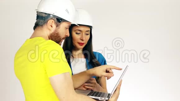 男性和女性建筑工程师讨论项目和使用笔记本电脑视频的预览图