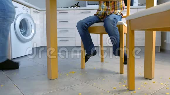 爸爸责骂儿子厨房地板上散落的食物让他打扫干净清理地板上的玉米片视频的预览图