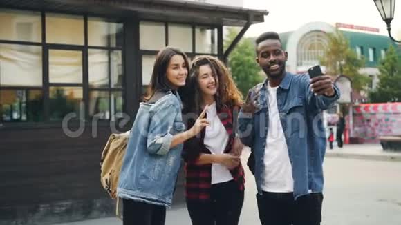 快乐的非裔美国人正在和朋友一起自拍漂亮的白人女孩站在街上摆姿势抱着她视频的预览图