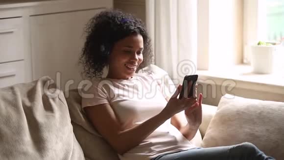 快乐的非洲年轻女士戴着无线耳机视频的预览图