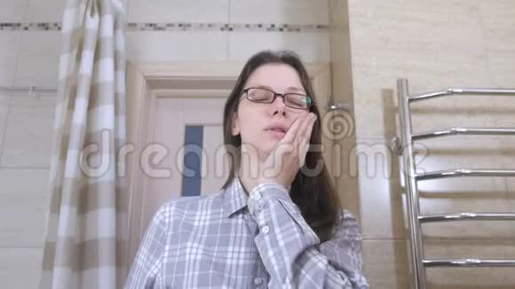 盥洗室里戴着眼镜的疲惫的女人打着自己的脸颊醒来视频的预览图