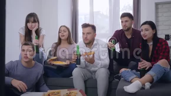 情绪激动的球迷朋友们在电视上观看体育锦标赛开心地吃披萨喝啤酒视频的预览图