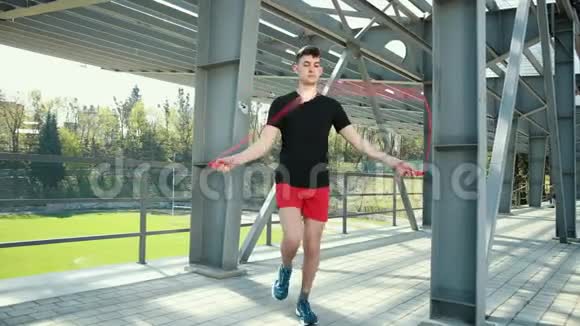 在金属架附近的平台上安装跳跃绳索的年轻人的肖像健身跳过健身户外盖伊巨人视频的预览图