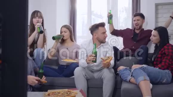 青少年聚会快乐的朋友和女孩一起玩一边看电视一边吃披萨一边喝瓶装啤酒视频的预览图
