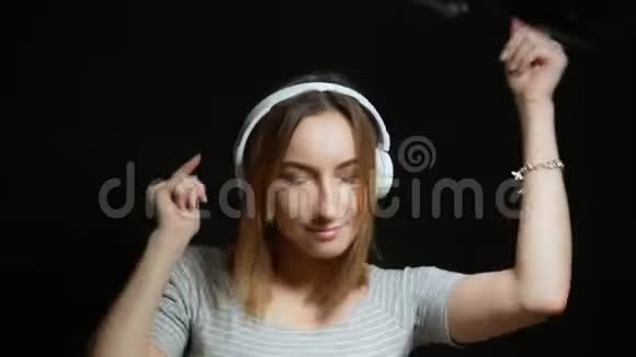 可爱的少女戴着黑色背景的耳机跳舞视频的预览图