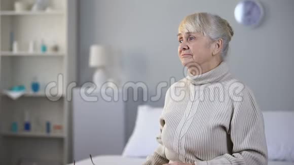 悲伤的老年妇女戴着眼镜看着相册思念着家人视频的预览图