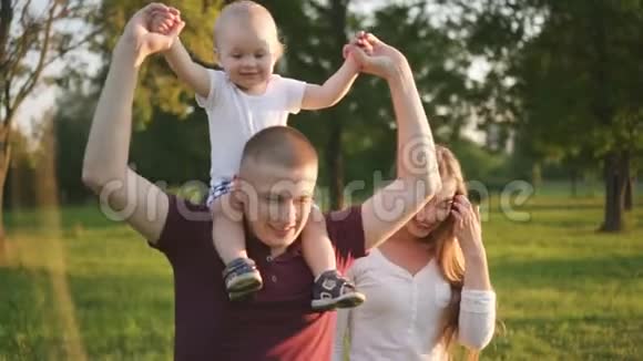 可爱的男孩坐在父亲的肩膀上在家庭第一次步行在公园视频的预览图
