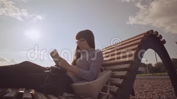 在凉爽的一天带平板电脑的自由职业者坐在鹅卵石海滩上的木制甲板椅上视频的预览图