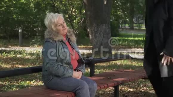 成熟的男人坐在公园的女人旁边视频的预览图