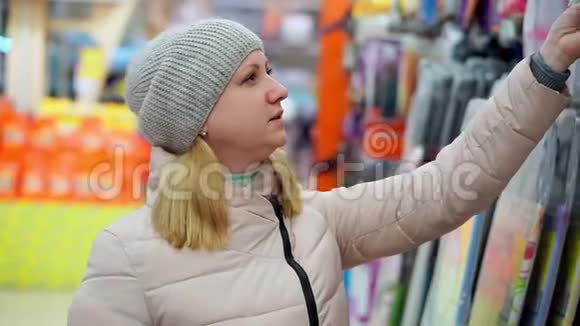 一个戴着帽子和羽绒服的中年妇女在超市里挑选商品视频的预览图