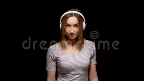 可爱的少女戴着黑色背景的耳机跳舞视频的预览图