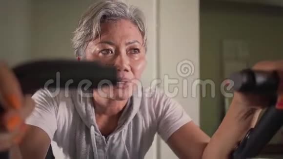 静态自行车射击中年迷人和出汗亚洲印度尼西亚妇女与白发训练出汗健身房视频的预览图