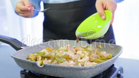 一个女人在煎锅里把木铲和鸡片和豆子和蘑菇混合在一起然后用酱油倒进去视频的预览图