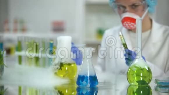 实验室研究人员在带绿色植物的试管中加入蓝色液体物质视频的预览图