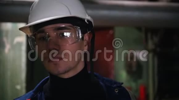 一位戴着防护眼镜的年轻工程师在工厂里走来走去视频的预览图