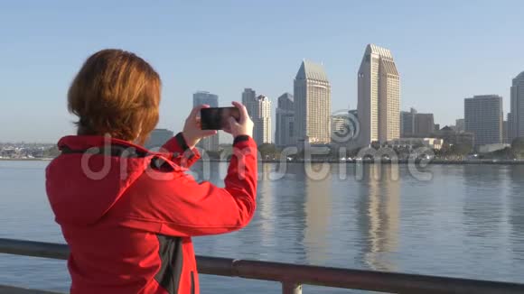 女旅行者用电话拍摄街道全景照片视频的预览图