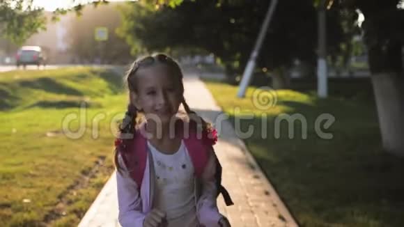 带背包的年轻女孩在阳光下快乐的微笑着带着辫子的青少年在耀斑的阳光下上学概念视频的预览图